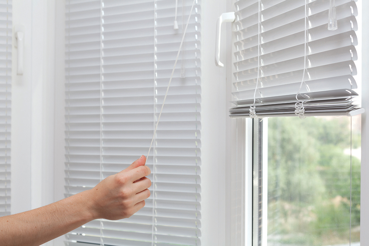Girls hand raise the white blinds with a cord